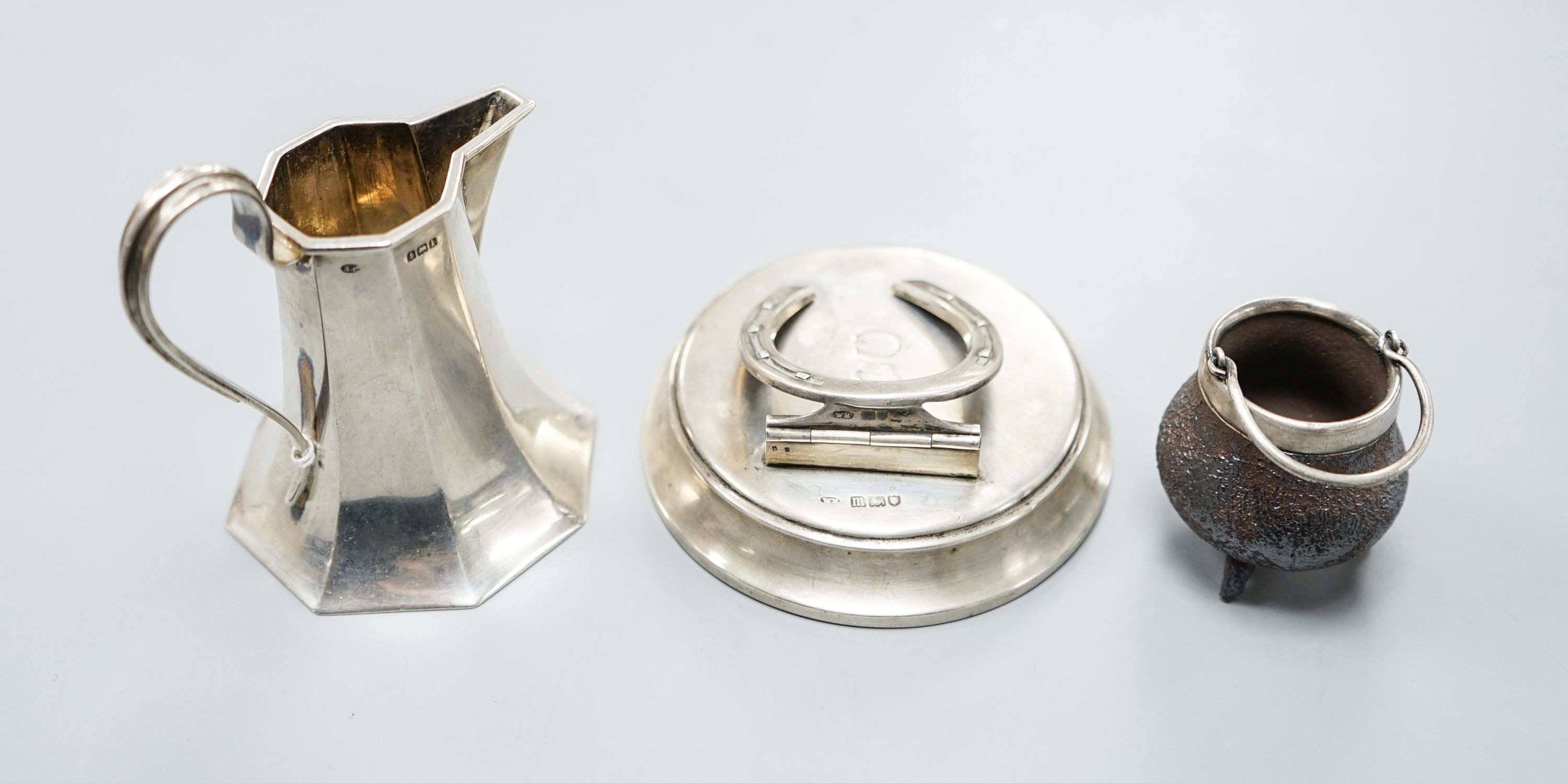 An Edwardian silver horseshoe letter clip, London, 1907, 86mm, a silver cream jug and a silver mounted Doulton Lambeth stoneware miniature cauldron.